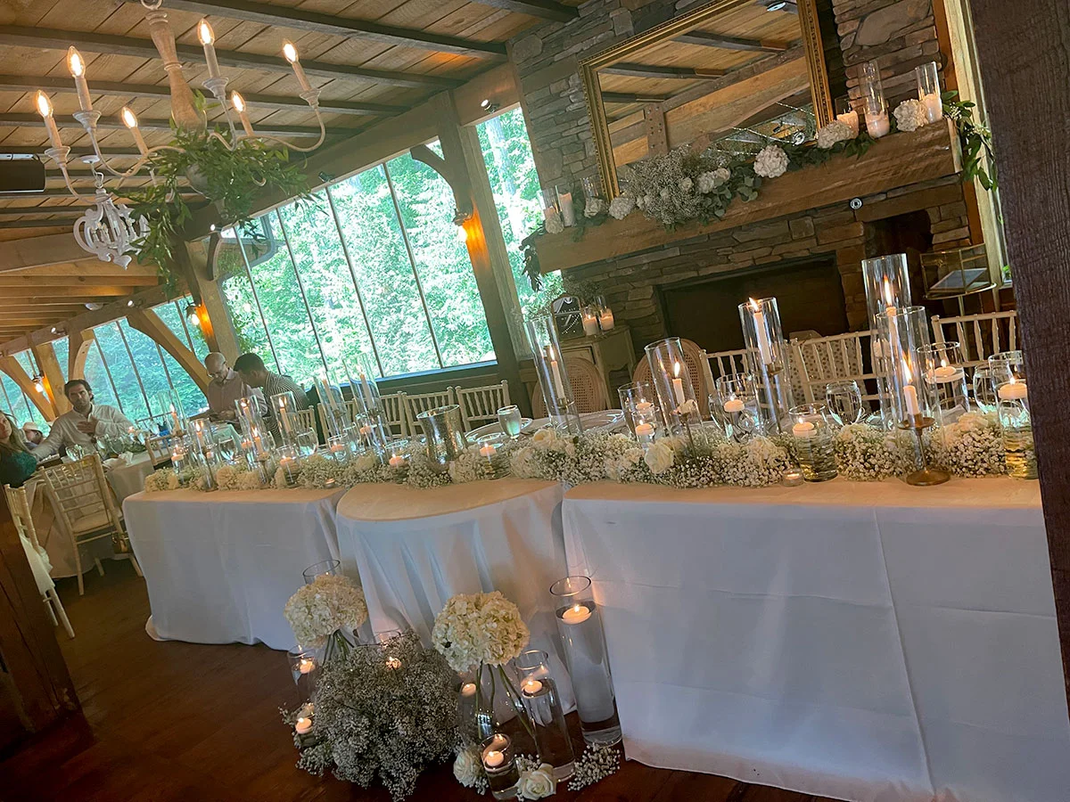 A long table with white linens and candles.