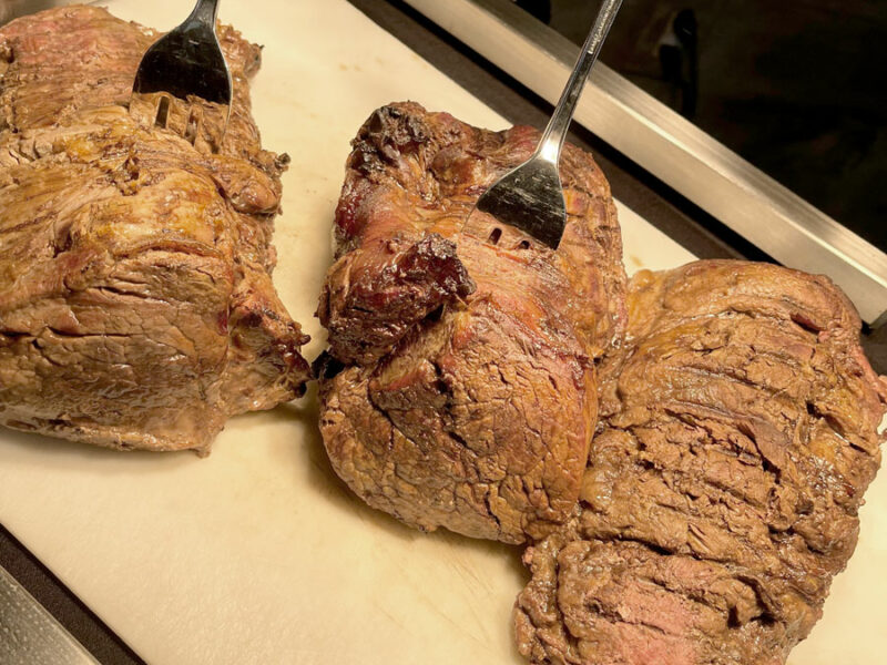 Two pieces of meat prepared by corporate caterers on a cutting board.