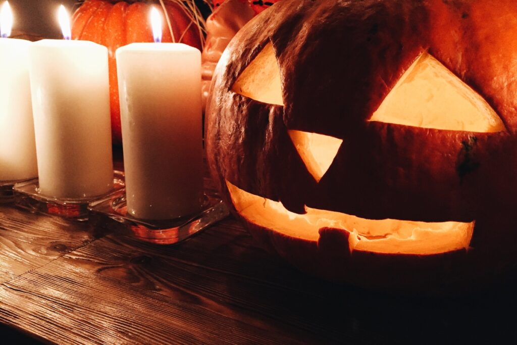 A festive fall party table with a jack o lantern and candles.