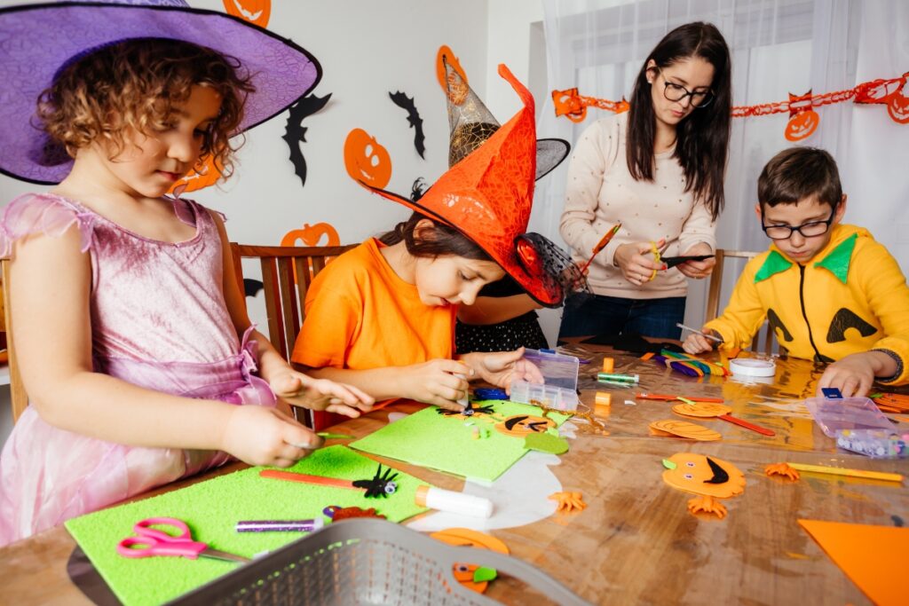 A group of children are making fall party crafts at a table.