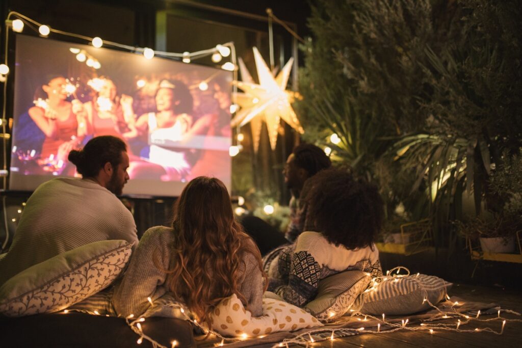 A fall party with people watching a movie outdoors.