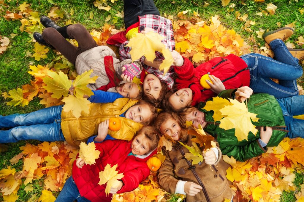 Fall party idea: Children enjoying a pile of leaves together.