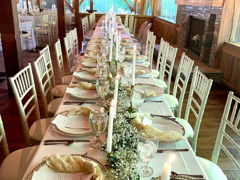 A long table with white linens and candles.