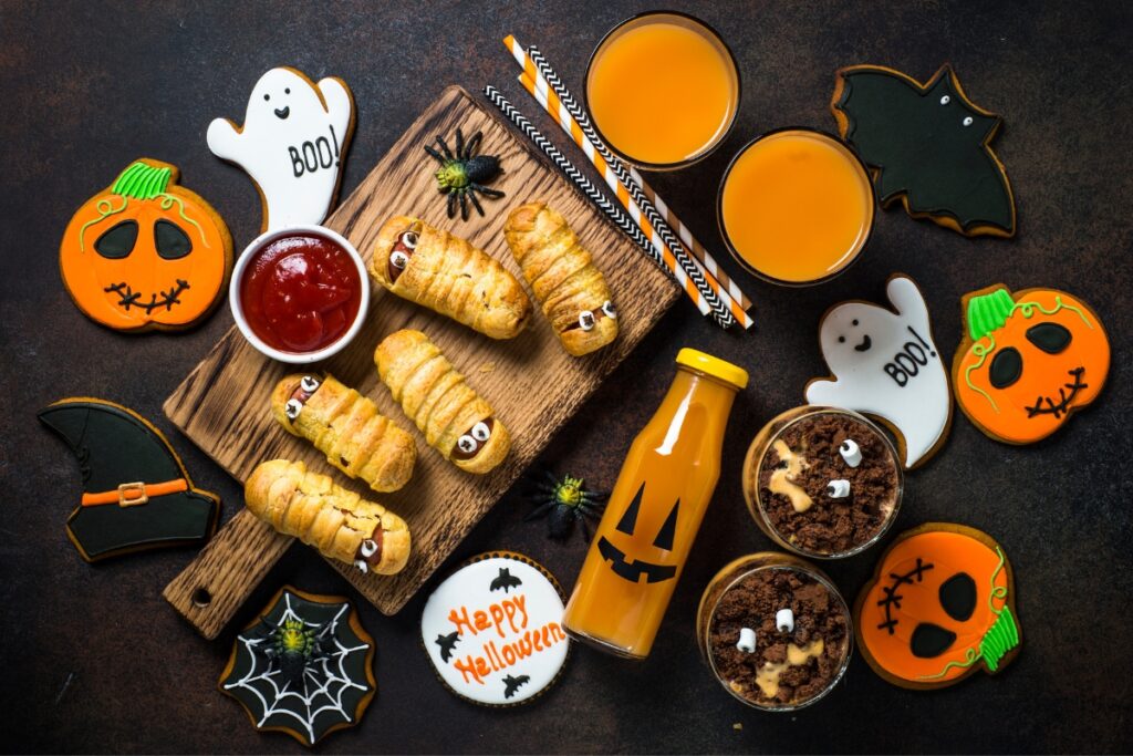 Spooky Halloween treats and drinks on a wooden cutting board.