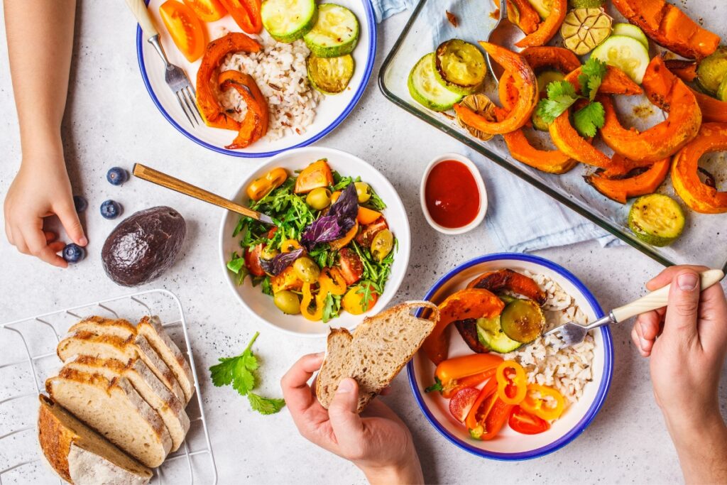 A group of people enjoying a plate of vegetables and bread during their Thanksgiving traditions.