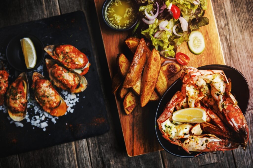 A plate of lobster, fries and lemons on a wooden table, showcasing a delectable twist on Thanksgiving traditions.