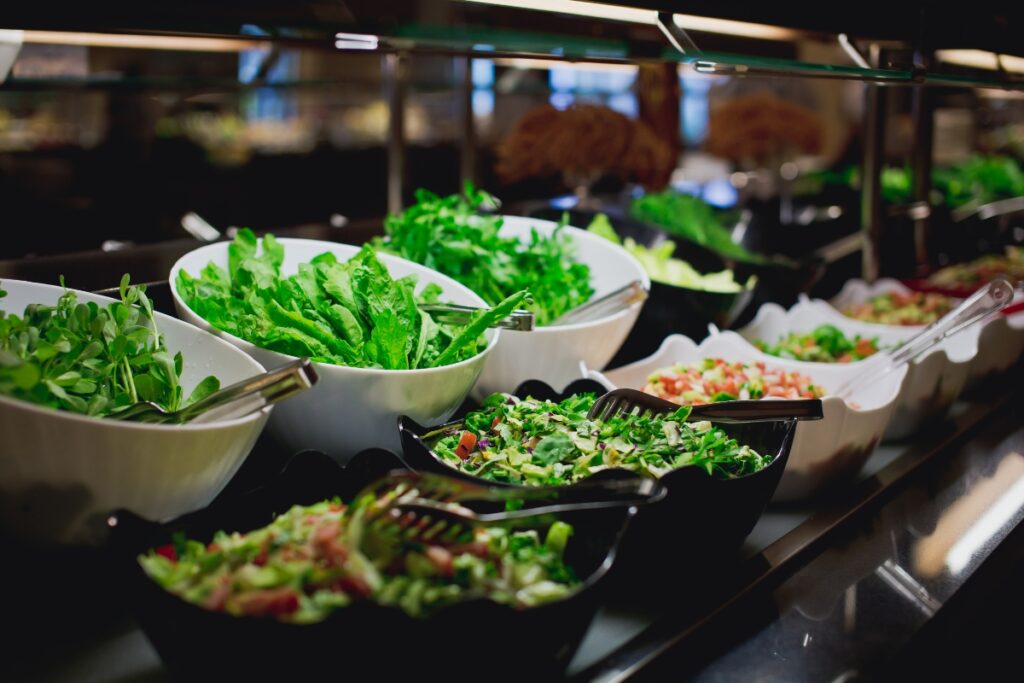 A variety of salads are displayed in bowls on a buffet counter, offering an assortment of delicious food options.