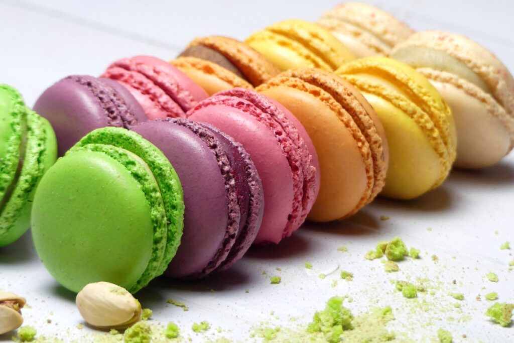 Rainbow macarons on a white surface, perfect for dessert catering at parties.