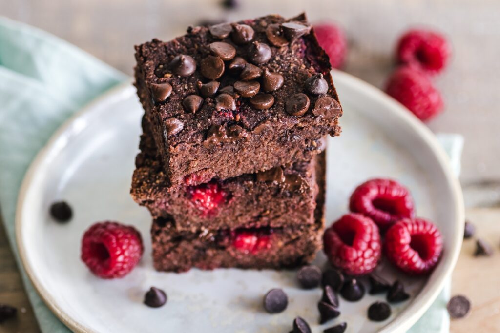 A delicious stack of chocolate brownies with raspberries, perfect for dessert catering at parties.