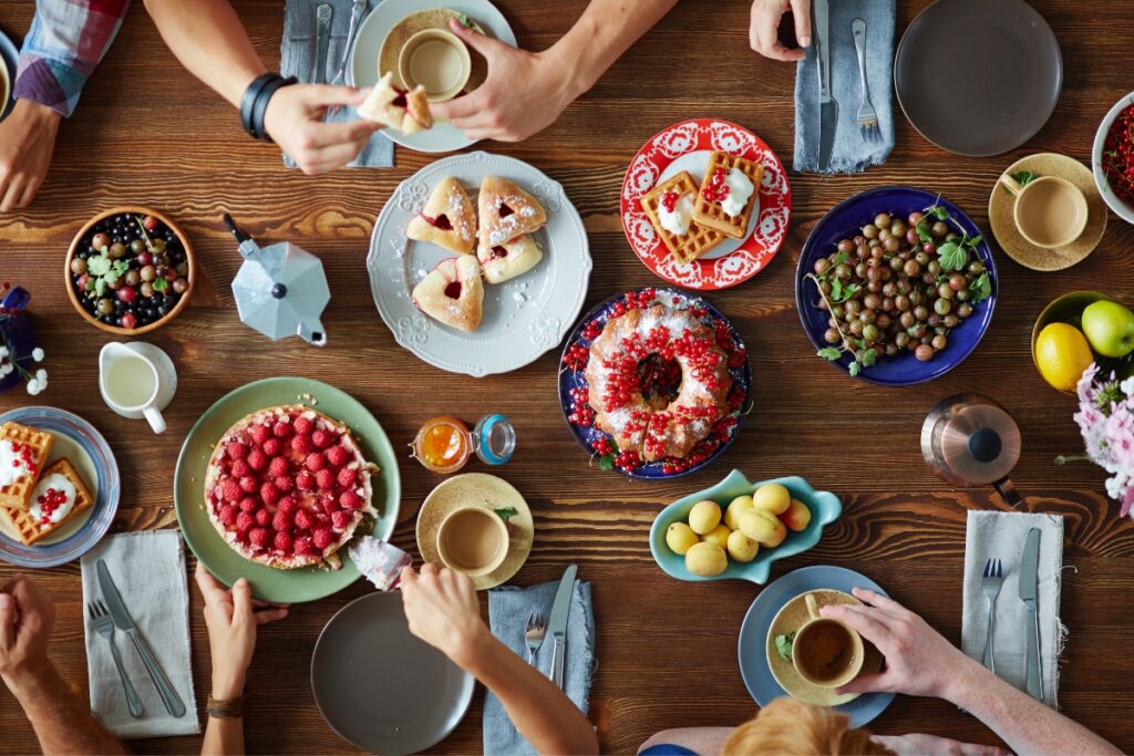 A group of people sitting around a table with plates of food, enjoying a scrumptious dessert during an exquisite party catering experience.