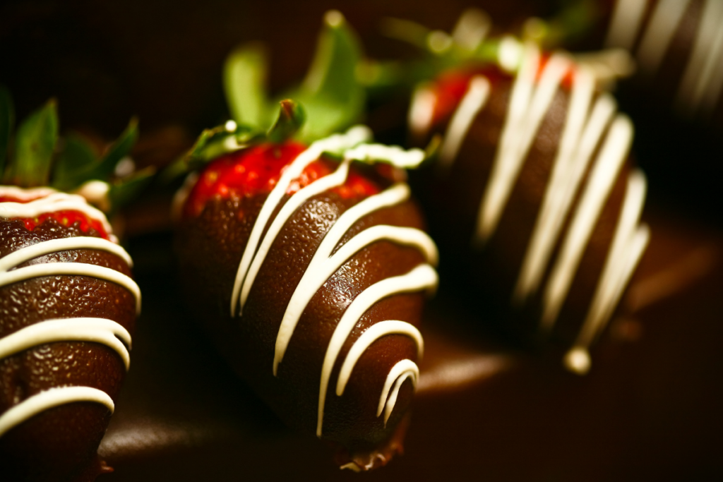 A close up of chocolate strawberries with white icing.