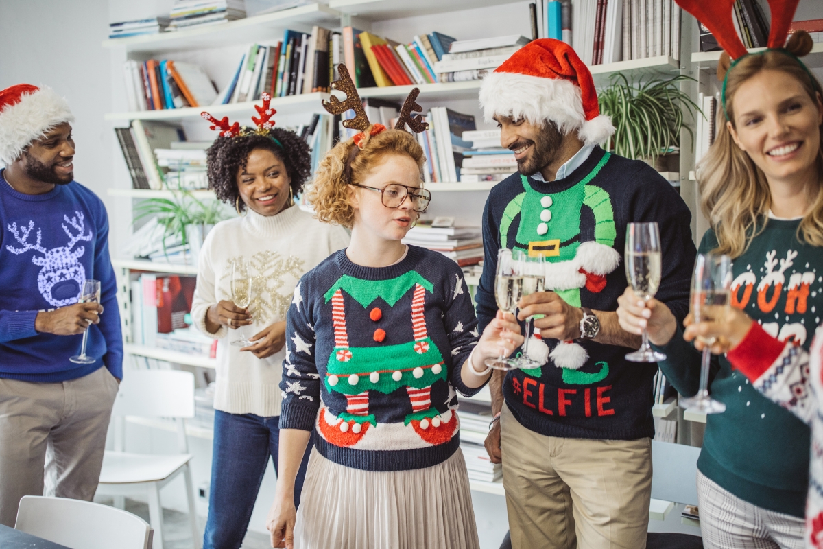 An office hosting an ugly sweater party with colleagues donning festive and outrageous Christmas sweaters.