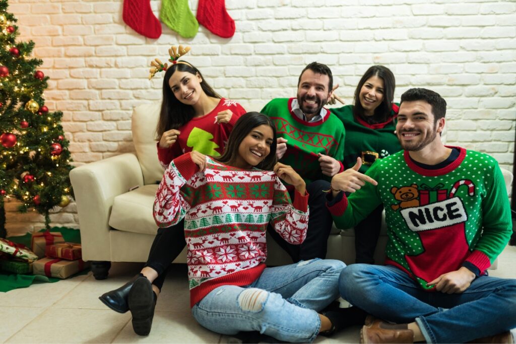 A group of people in ugly Christmas sweaters enjoying an ugly sweater party on a cozy couch.
