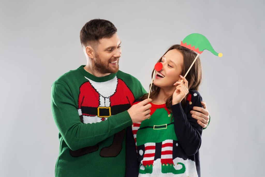 A couple attending an ugly sweater party while wearing their festive Christmas sweaters.