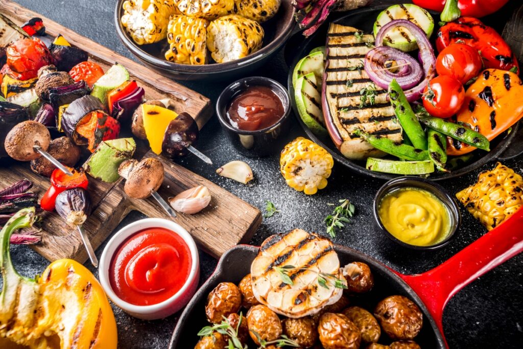 A variety of plant-based grilled vegetables and vegan meats on a table.
