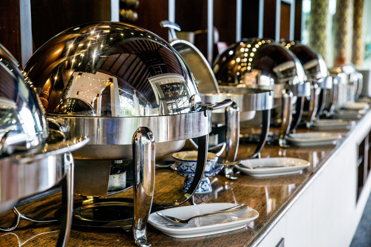 A line of stainless steel utensils on a counter for catering purposes.