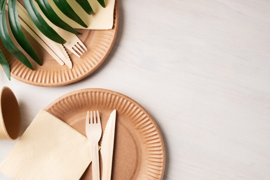 Eco friendly catering with paper plates and utensils on a wooden table.