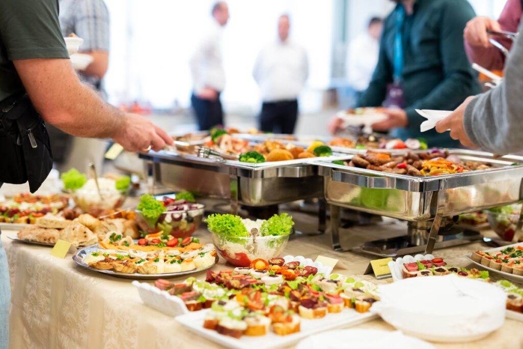 A group of people engaged in food styling while serving food at a buffet.