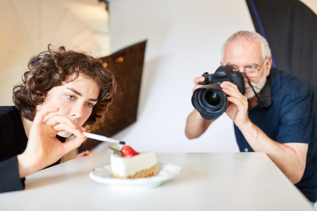 A man is taking a picture of a cake with food styling techniques using a camera.