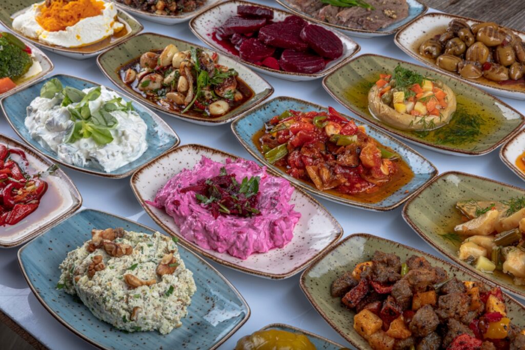 An assortment of colorful Mediterranean fusion cuisine appetizers arranged on a wooden table.