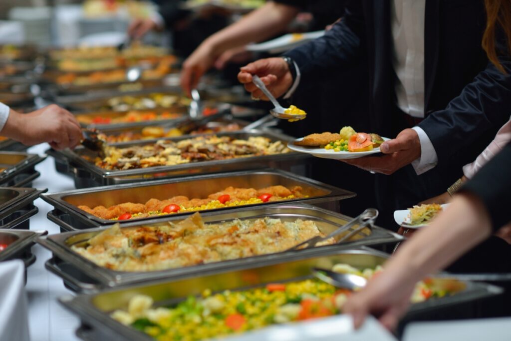 People serving themselves from event food stations with a variety of dishes in chafing dishes at a formal event.