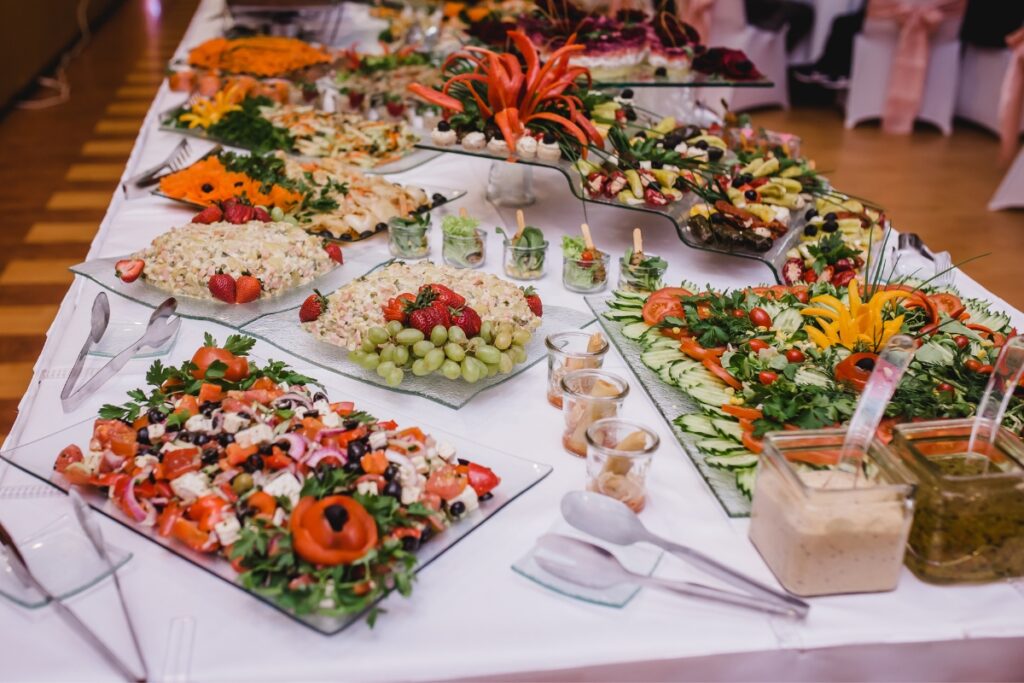 A buffet table featuring a variety of colorful and beautifully arranged healthy dishes including salads, fruits, and dips.