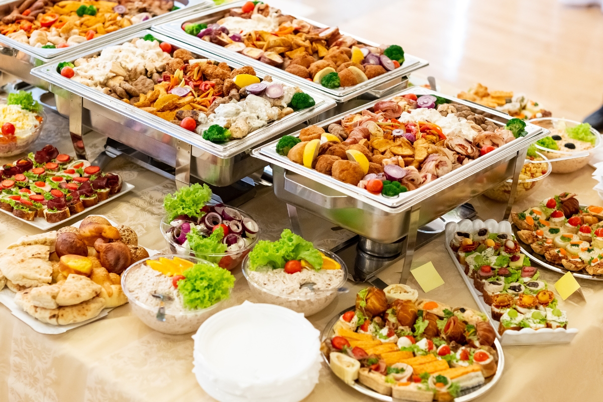 An assortment of catered food, including trays of meats, vegetables, and various appetizers, displayed on a table provides the perfect office catering solution.