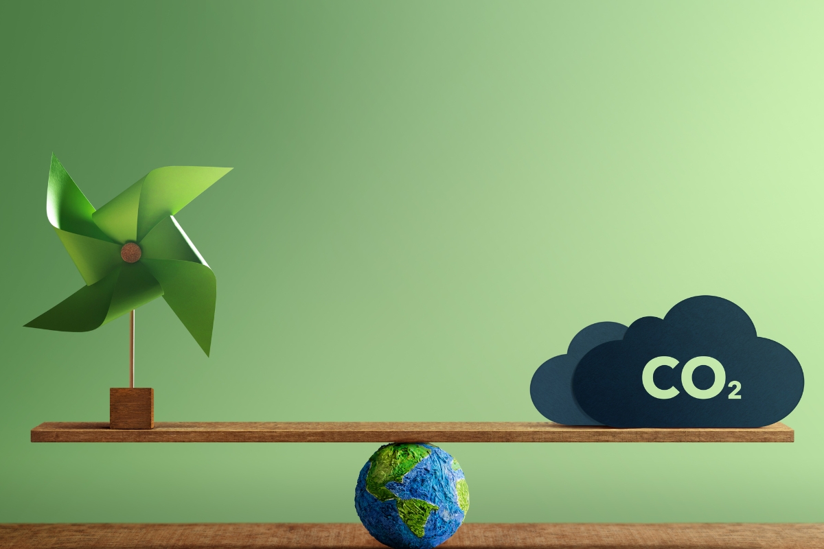 A small green pinwheel and a CO2 cloud cutout balance on a shelf over a mini globe, symbolizing the harmony between eco-conscious catering practices and carbon emissions.