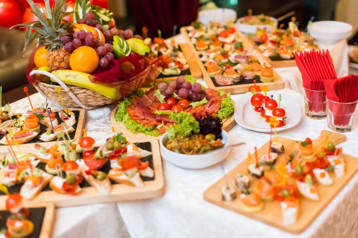 A table is filled with assorted appetizers, including skewered bites, sliced meats, fruits, and vegetables, all neatly arranged for a buffet-style presentation by our custom catering service.