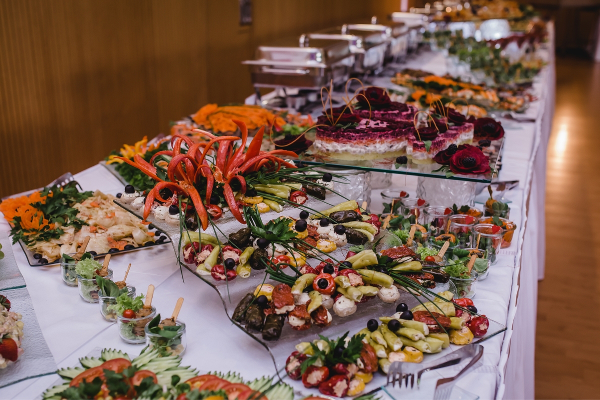 A buffet table filled with custom catering options, featuring various appetizers like vegetables, dips, and decorative platters, set in an elegant banquet room.