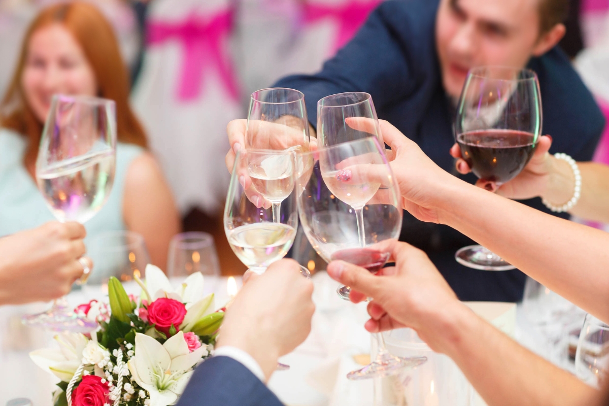 People clinking wine glasses in a celebratory toast around a table with a floral centerpiece, enjoying the exquisite delights of custom catering.