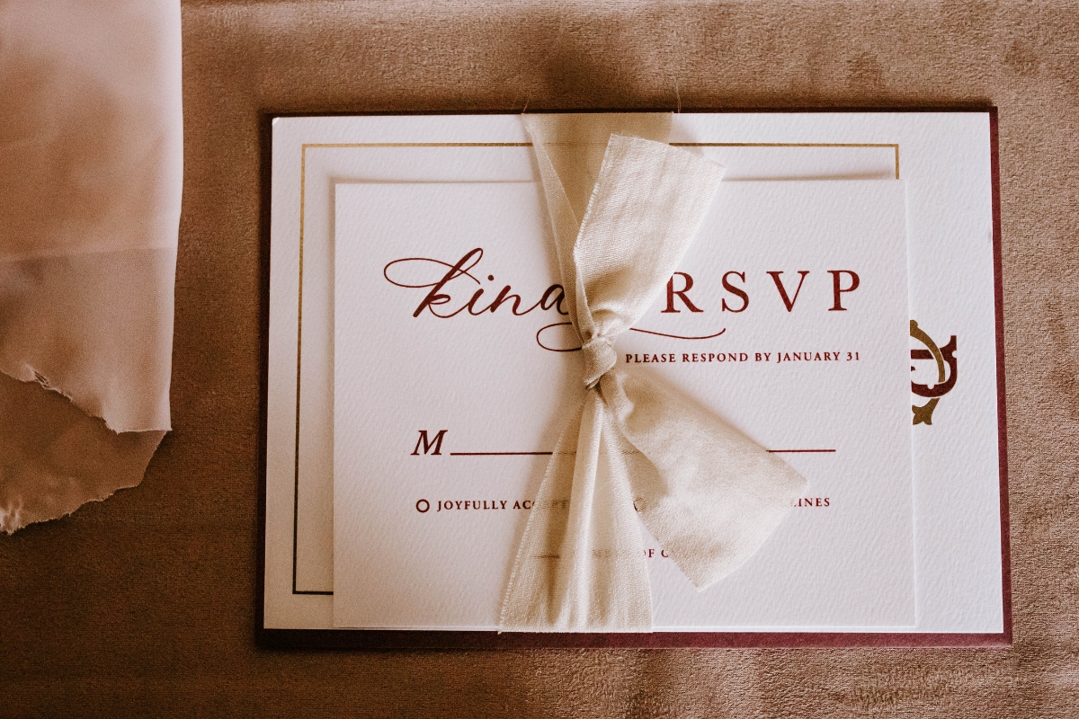 An RSVP card with elegant script, essential for event planning, is tied with a beige ribbon and placed on a textured surface.