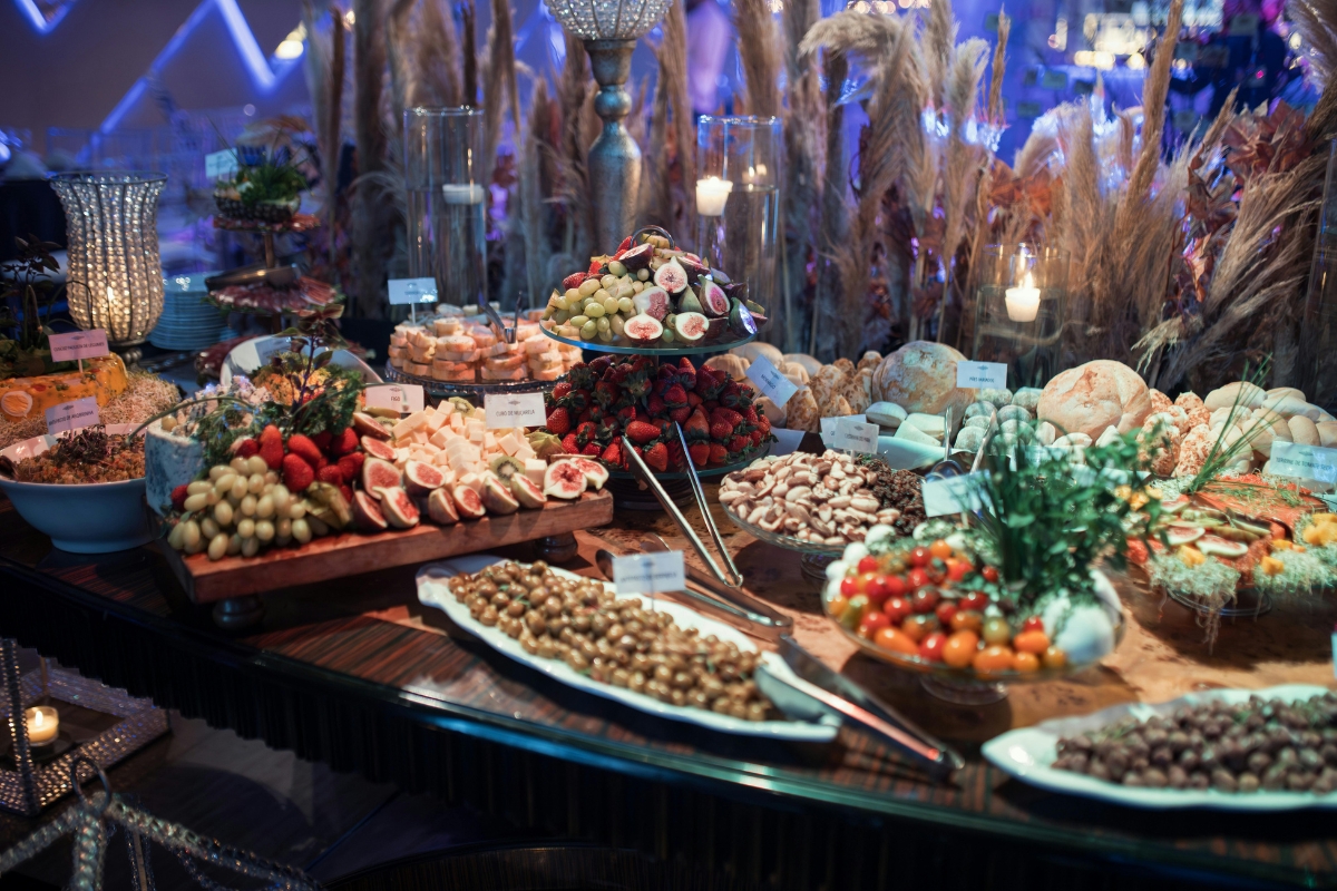 Creating a VIP Catering Experience at Summer Music Festivals 3 A buffet table is arranged with assorted fruits, vegetables, breads, cheeses, and labeled dishes, under decorative lighting and surrounded by ornamental grasses—perfect for the lively atmosphere of summer music festivals.
