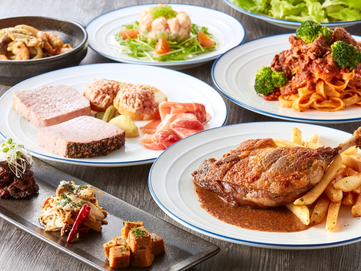 Planning a Fall-Themed Wedding Reception Menu: Seasonal Delights for Your Big Day 3 A variety of plated dishes including steak with fries, pasta with sauce and broccoli, cold cuts, seafood salad, and assorted appetizers on a wooden table, perfect for a cozy Fall-Themed Wedding Reception.