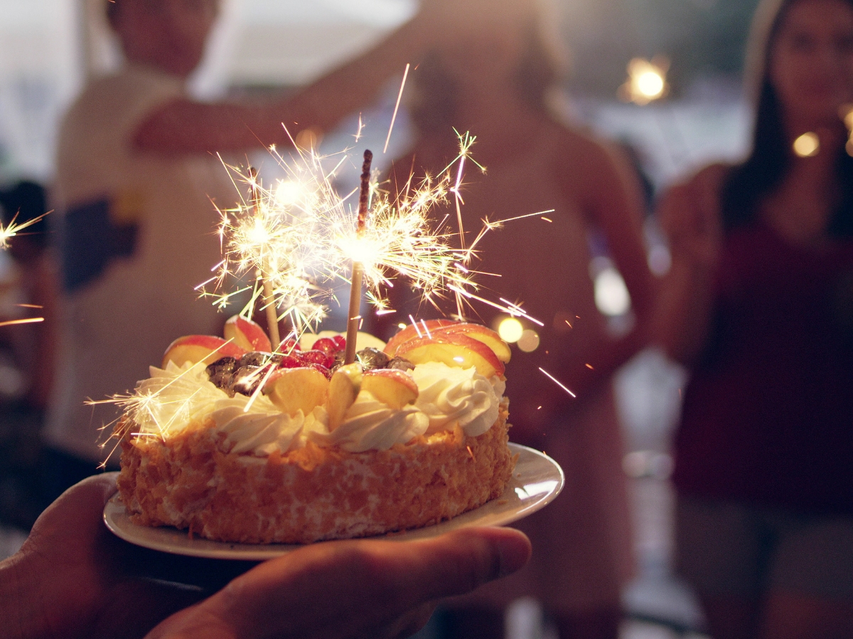 A hand holding a cake with sparklers on it, perfect for your next birthday party catering celebration.