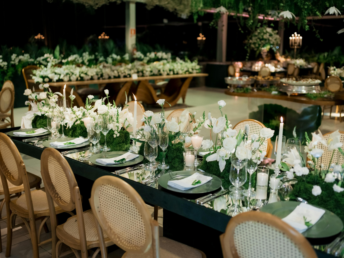 Charming Rehearsal Dinner Catering in Metro Atlanta: Personalized Wedding Catering Solutions 6 Elegant banquet table set with white flowers, candles, glassware, and plates; wooden chairs surround the table in a spacious, decorated event hall—perfect for hosting a refined rehearsal dinner catering experience.